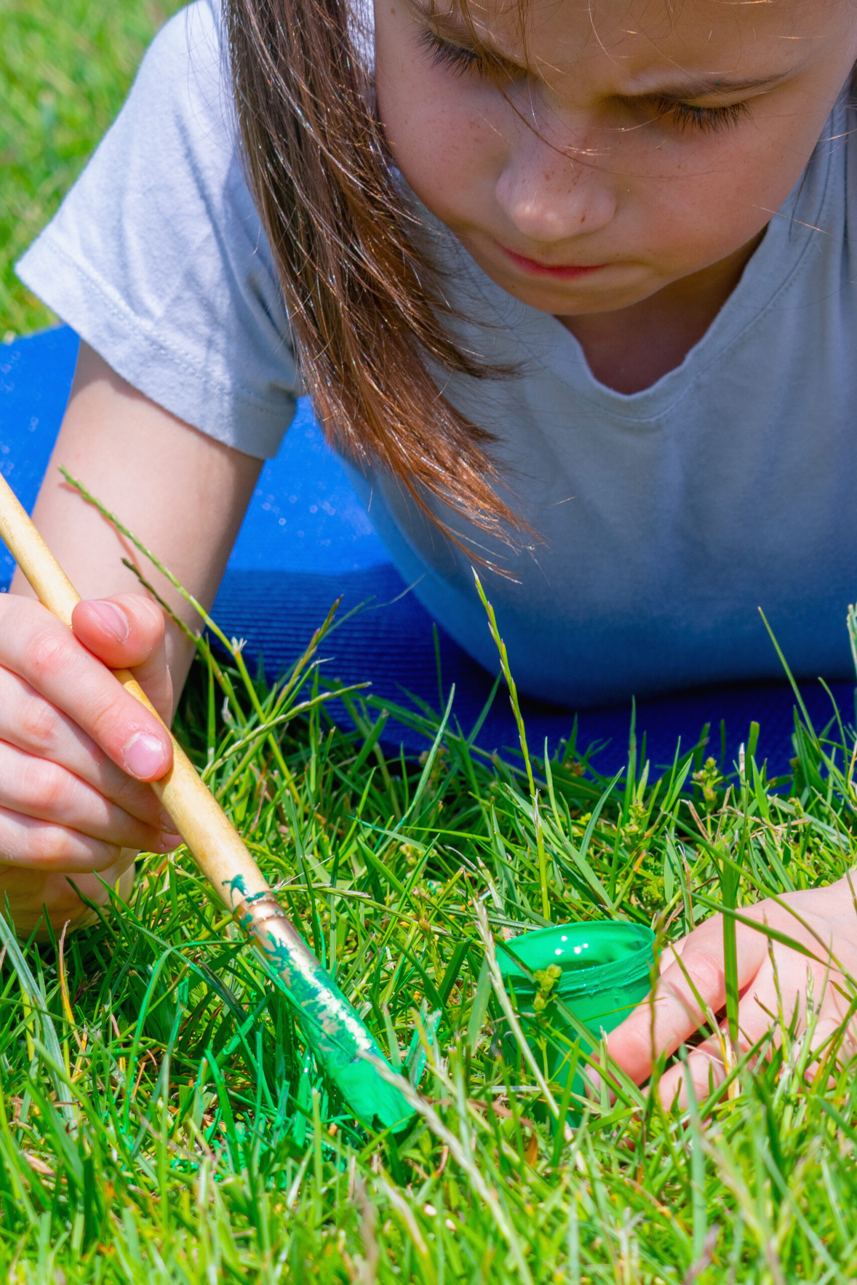 Conceptual image: Obsessive-compulsive disorder (OCD). Portrait of young beautiful girl paints the grass green because it is not green enough. Vertical image.